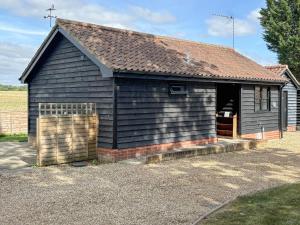 a small black building with a window and a fence at Rose Chalet in Framlingham