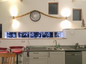 a kitchen with a sink and a clock on the wall at Llety'r Saer in Hirnant