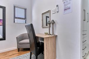 a room with a desk with a chair and a mirror at 4 Kiaat Suites in Klerksdorp