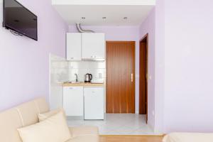 a living room with a white couch and a kitchen at Mala Mara in Kaštela