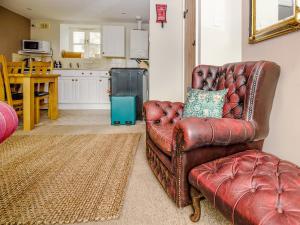 a leather chair in a living room with a kitchen at Keepers Cottage - Ukc3950 in Puncknowle