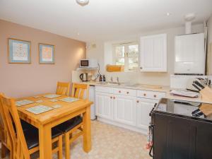a kitchen with white cabinets and a wooden table with chairs at Keepers Cottage - Ukc3950 in Puncknowle