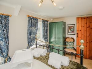 a bedroom with a bed and a chair and curtains at Keepers Cottage - Ukc3950 in Puncknowle +34 photos
