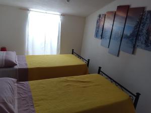 two beds in a room with yellow sheets and a window at Casa vacanze nel Parco della Majella in Montenerodomo