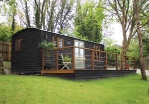 a black tiny house sitting on a grass field at Chycara House in Truro