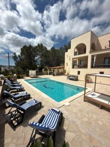 a swimming pool with lounge chairs next to a building at Beautiful Villa Rafaella in Sant Rafael de Sa Creu