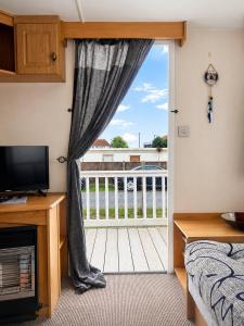 a bedroom with a door open to a balcony at The Hemsbee Static caravan 117 Sandsgate Hemsby in Hemsby