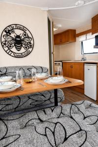 a living room with a table and a kitchen at The Hemsbee Static caravan 117 Sandsgate Hemsby in Hemsby +21 photos