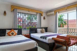 a bedroom with two beds and a balcony with a window at Bou Phanith Villa in Siem Reap