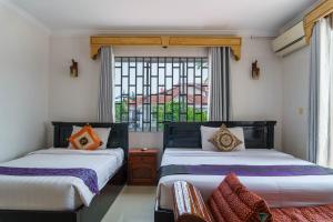 two beds in a room with a window at Bou Phanith Villa in Siem Reap +34 photos
