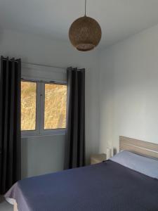 a bedroom with a blue bed and a window at Eagle's Nest Kythnos in Flampouria