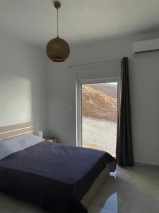 a bedroom with a bed and a large window at Eagle's Nest Kythnos in Flampouria