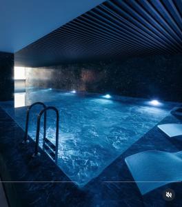 a large swimming pool with blue water at night at PREMIUM Apartament & Wellness with jacuzzi, sauna , gym , pool in Bucharest +24 photos