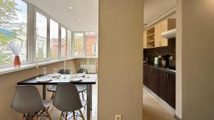 a kitchen with a table and some chairs and windows at Calm Central Apartment in Kharkiv