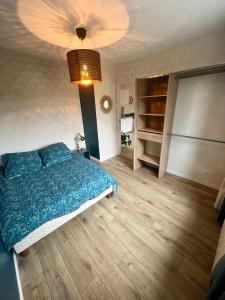 a bedroom with a bed with a blue comforter at Appartement proche Eurexpo Aéroport Genas Centre in Genas