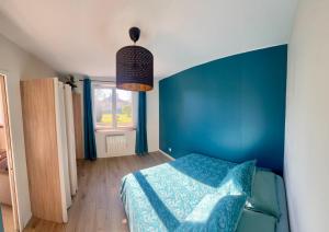 a blue bedroom with a bed and a blue wall at Appartement proche Eurexpo Aéroport Genas Centre in Genas