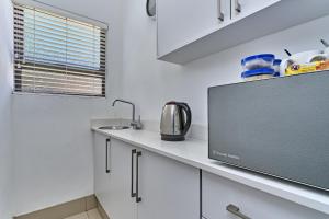 a kitchen with white cabinets and a sink at 2 Kiaat Suites in Klerksdorp