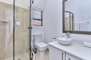 a bathroom with a toilet and a sink and a shower at 2 Kiaat Suites in Klerksdorp