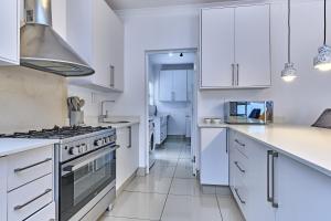 a kitchen with white cabinets and a stove at 2 Kiaat Suites in Klerksdorp