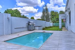 a swimming pool in a yard next to a white fence at 2 Kiaat Suites in Klerksdorp