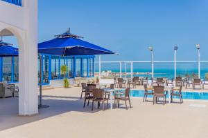 a patio with tables and chairs with the ocean in the background at Pallax hotel in Zarzis