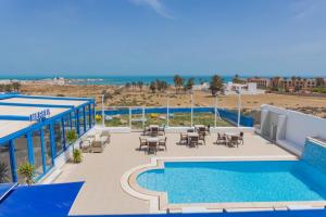 a pool with tables and chairs next to a beach at Pallax hotel in Zarzis +64 photos