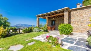 a stone patio with a pergola and flowers at Cortijo Noguera La Taha - Pitres by Ruralidays in Granada