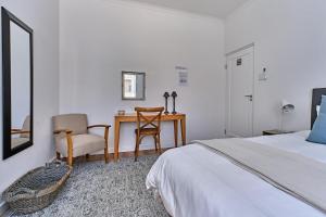 a bedroom with a bed and a desk and a chair at 3 Kiaat Suites in Klerksdorp