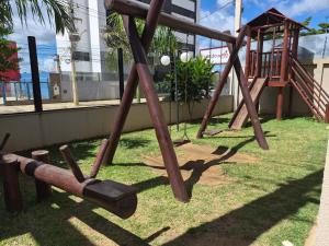 a playground with a wooden swing set on the grass at AP Climatizado aconchego com Mercado em frente in Vitória da Conquista