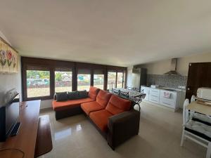 a living room with an orange couch and a kitchen at La Buena Vida, el Palmar in El Palmar