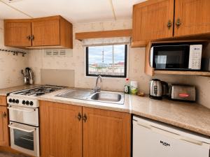 a small kitchen with a sink and a microwave at The Hemsbee Static caravan 117 Sandsgate Hemsby in Hemsby