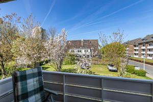 a balcony with a chair and trees and a street at Haus Passat in Büsum