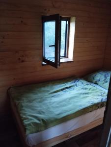 a bed in a log cabin with a window at Domček pri vode Pohoda in Teplý Vrch