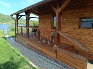 a wooden cabin with a deck with a view of the water at Domček pri vode Pohoda in Teplý Vrch