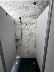 a walk in shower with a white marble wall at Хостел in Sumy