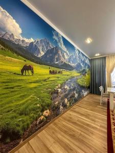 a mural of horses in a field with mountains at Alcha Hotel Karakol in Karakol