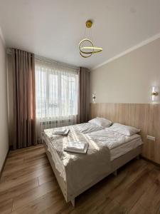 a bedroom with a bed and a large window at Alcha Hotel Karakol in Karakol +19 photos