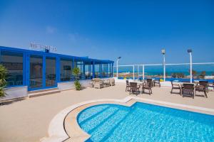 a swimming pool with tables and chairs next to a building at Pallax hotel in Zarzis