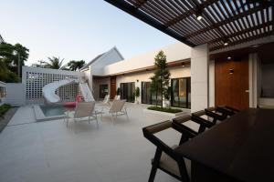 an outdoor patio with chairs and a water slide at Sea Vibes Pool Villa in Ban Bo So