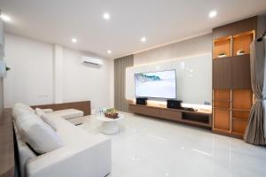 a living room with a white couch and a flat screen tv at Sea Vibes Pool Villa in Ban Bo So
