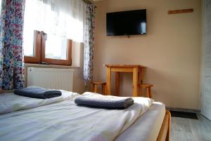 two beds in a room with a tv on the wall at U Jasia - Agroturystyka in Bańska Niżna