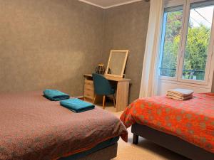 a bedroom with two beds and a desk and a window at Au bord de l eau in Villabé