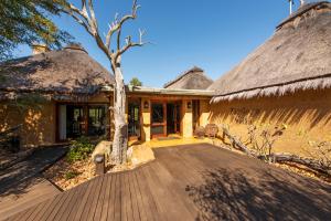 a house with thatched roofs with a tree in front at Jabulani Safari Relais & Chateaux in Kapama Private Game Reserve