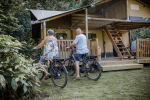 a man and woman riding bikes in front of a house at Arden Parks Baalse Hei in Turnhout