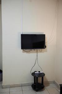 a flat screen tv hanging on a wall with a table at Niyonest Guesthouse in Harare