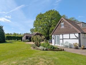a house with a garage and a yard at Fewhurst Cottage - Billingshurst in Billingshurst