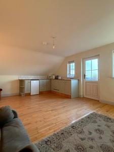 an empty living room with a kitchen and a couch at The Hilltop Hideaway in Enniskillen