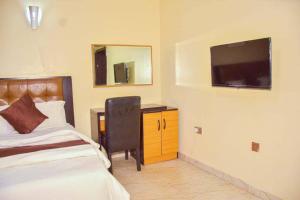 a bedroom with a bed and a desk and a television at Daikon Garden Hotel in Ekwulobia