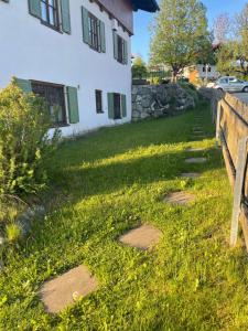 a house withestones in the grass next to a fence at Gästehaus zum Stricker, Eckweg 9 in Bad Bayersoien