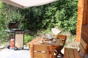 a grill and a wooden table with a table and chairs at Chalet Hinter dem Rot Stei, private wellness, in ski and hiking area of Zermatt in Zermatt